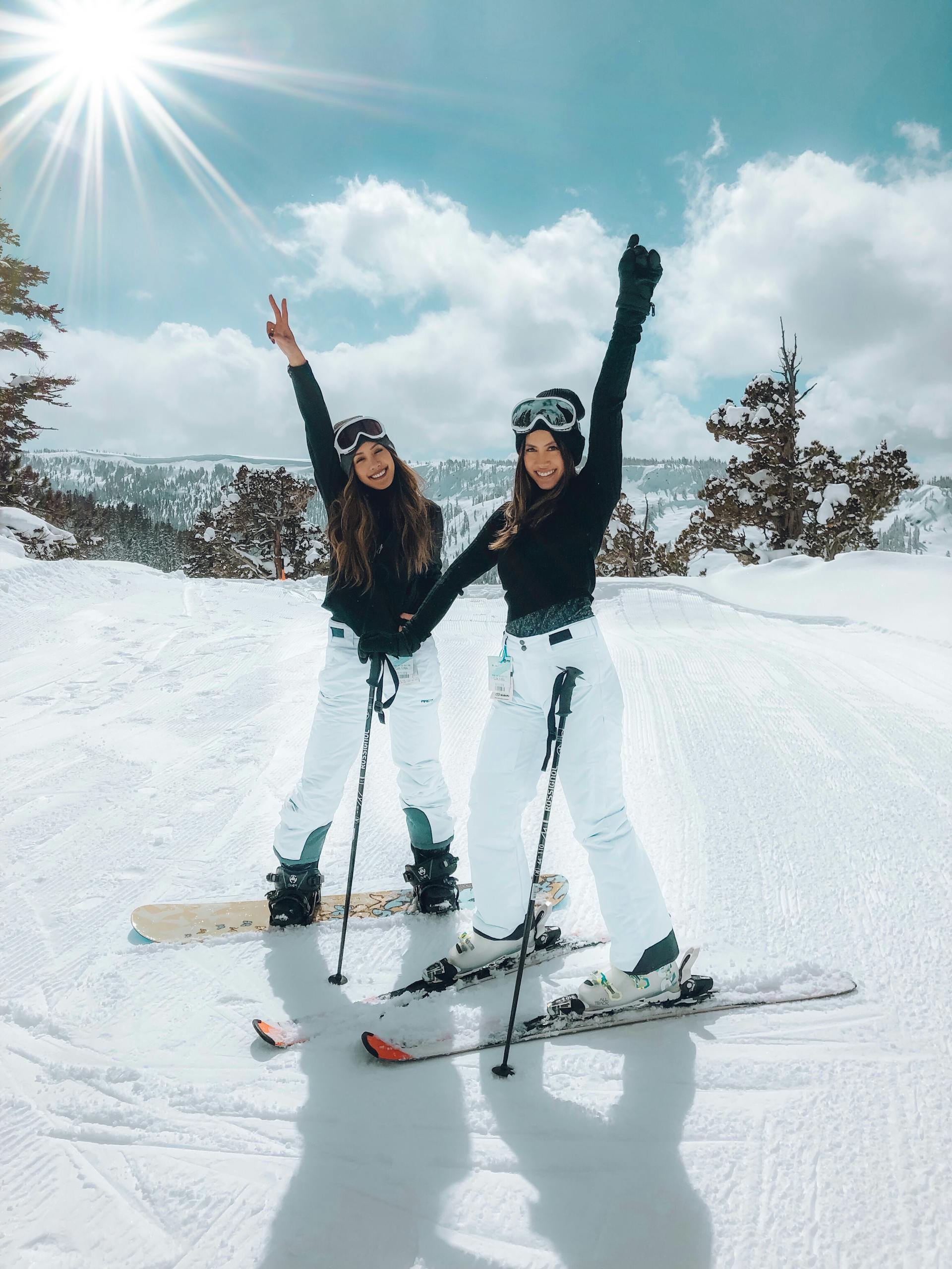 Two women posing on a snowy slope, enjoying a bright winter day of skiing and snowboarding.